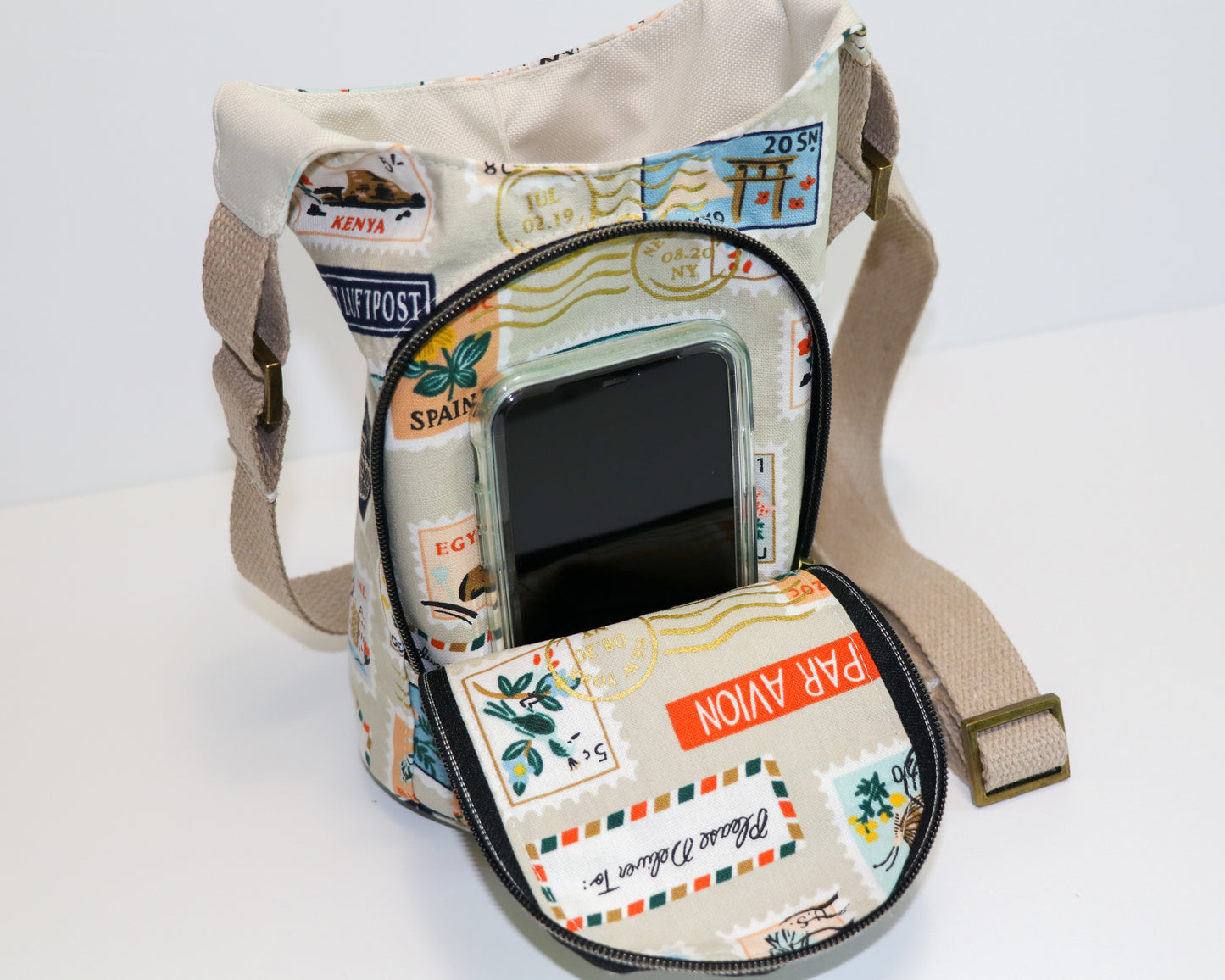 postage stamps print water bottle sling, front view with pocket open, phone inside