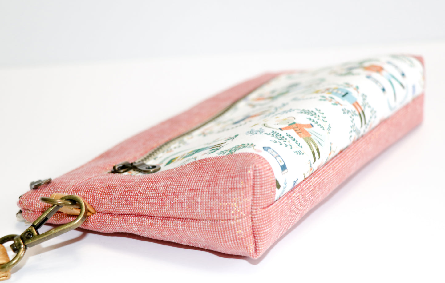 Nutcracker print and rose metallic linen wristlet laid on side