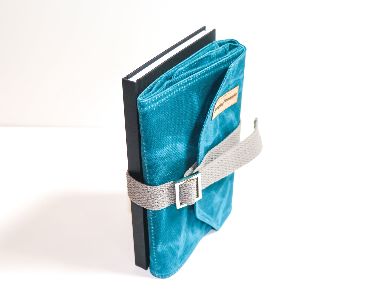 large teal artist roll, front view standing up on end strapped to sketchbook