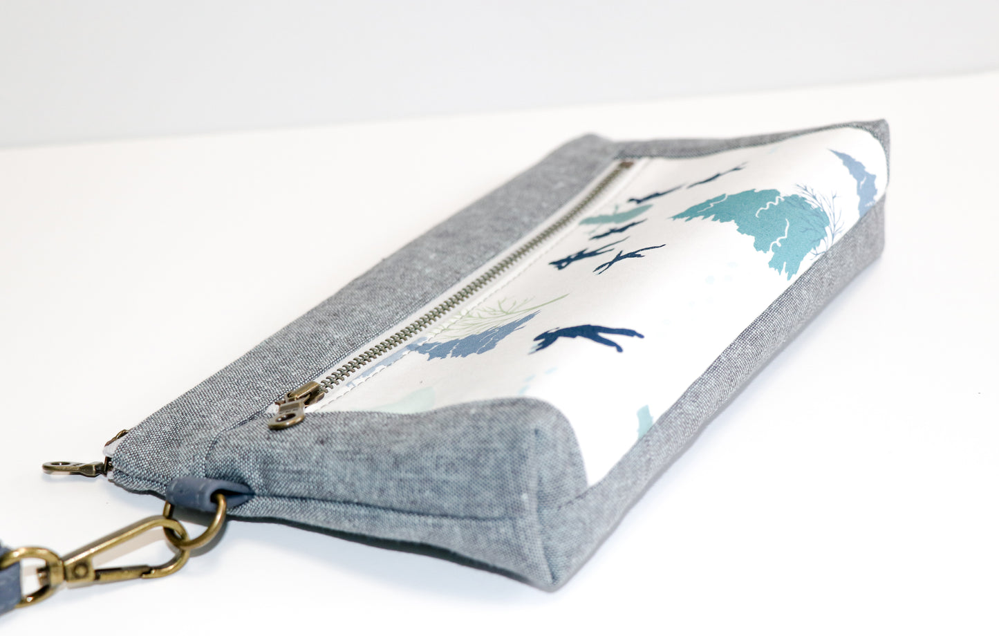 kids playing in the snow and grey/blue linen wristlet laid on side